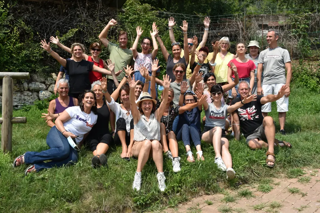 Un gruppo all’aperto con le mani alzate dopo un’attività condivisa.